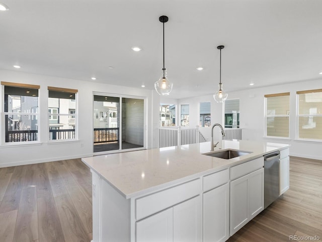 kitchen with light wood-style flooring, light stone counters, a sink, white cabinetry, and stainless steel dishwasher