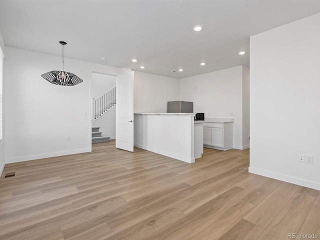unfurnished living room with light wood finished floors, recessed lighting, visible vents, stairway, and baseboards