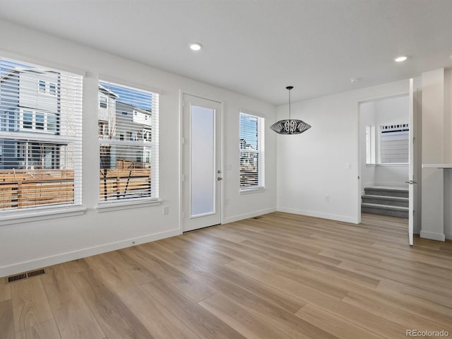 unfurnished dining area with stairs, light wood-type flooring, visible vents, and baseboards