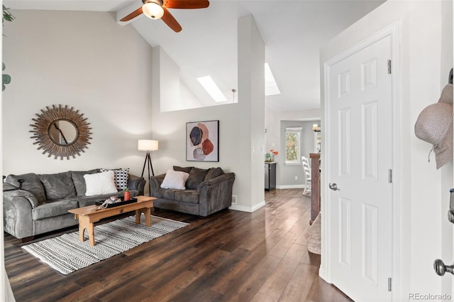 living room featuring vaulted ceiling with skylight, dark wood-style floors, baseboards, and a ceiling fan