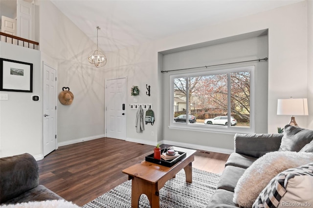 living area with baseboards, an inviting chandelier, and wood finished floors