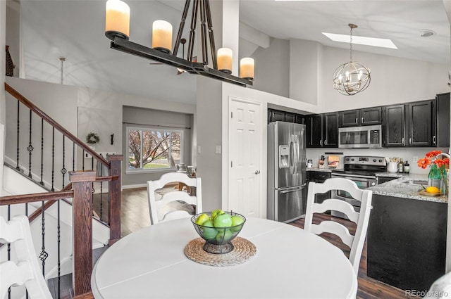 dining room featuring stairs, a notable chandelier, a skylight, and wood finished floors