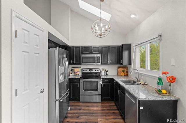 kitchen featuring a notable chandelier, a sink, dark cabinets, lofted ceiling with skylight, and stainless steel appliances