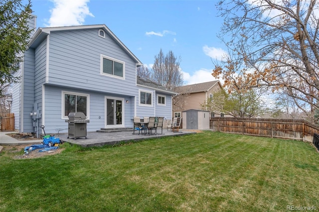 rear view of house featuring a patio area, a fenced backyard, an outbuilding, a lawn, and a storage unit