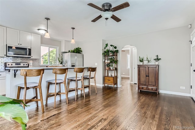 1171 Syracuse St, Denver, CO 80220 - kitchen with appliances with stainless steel finishes, arched walkways, a ceiling fan, a kitchen breakfast bar, and decorative backsplash