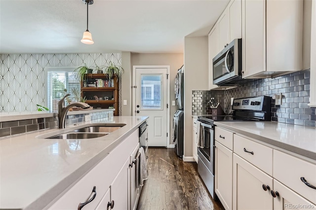 1171 Syracuse St, Denver, CO 80220 - kitchen featuring stainless steel appliances, a sink, stacked washer and clothes dryer, light countertops, and dark wood-type flooring