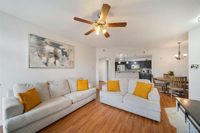 living room featuring ceiling fan with notable chandelier and light hardwood / wood-style floors