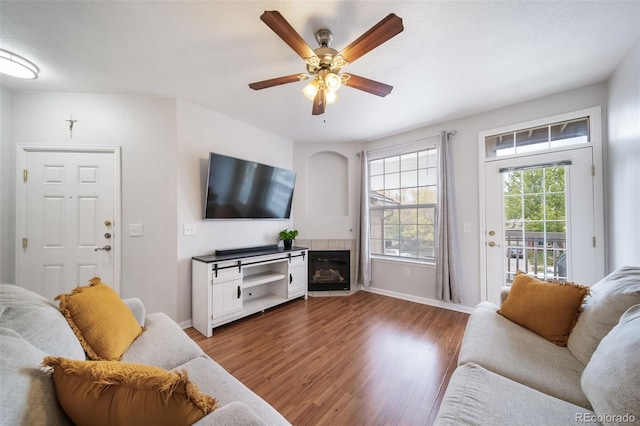 living room featuring ceiling fan, wood-type flooring, and a tile fireplace