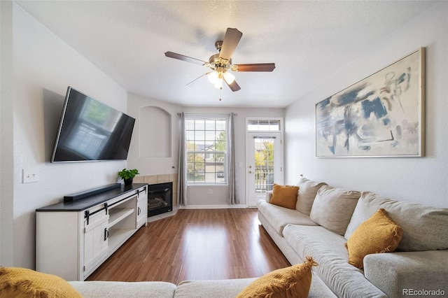 living room featuring dark wood-type flooring, a tile fireplace, and ceiling fan