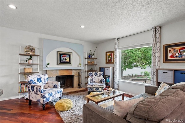 4194 S Kalispell St, Aurora, CO 80013 - living area featuring wood finished floors, a textured ceiling, a fireplace with raised hearth, and recessed lighting