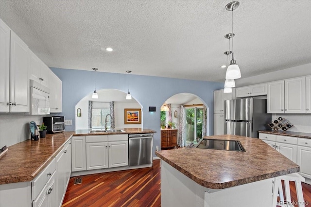 4194 S Kalispell St, Aurora, CO 80013 - kitchen with stainless steel appliances, arched walkways, dark countertops, a textured ceiling, and dark wood-type flooring