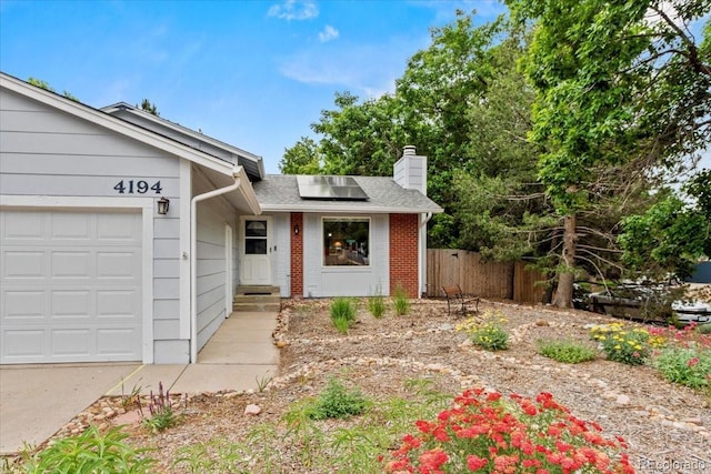 4194 S Kalispell St, Aurora, CO 80013 - single story home featuring a chimney, an attached garage, solar panels, brick siding, and a shingled roof