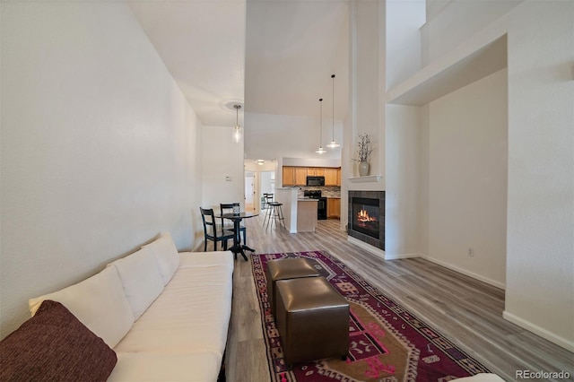5465 Zephyr St Unit 201, Arvada, CO 80002 - living room featuring a tiled fireplace, light wood-type flooring, and a towering ceiling