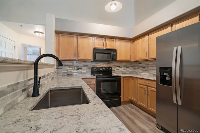 5465 Zephyr St Unit 201, Arvada, CO 80002 - kitchen with black appliances, light stone counters, and light wood-type flooring