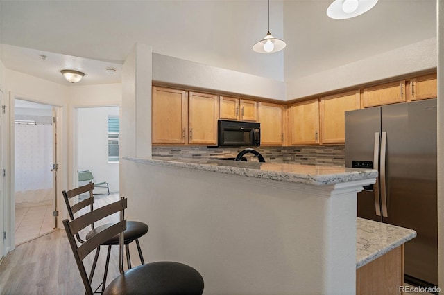 5465 Zephyr St Unit 201, Arvada, CO 80002 - kitchen with stainless steel fridge with ice dispenser, black microwave, backsplash, and light stone countertops
