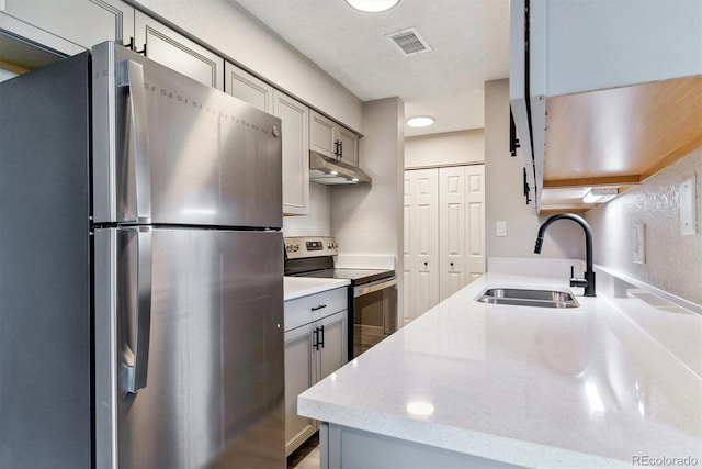 kitchen featuring light stone counters, sink, gray cabinetry, a textured ceiling, and stainless steel appliances