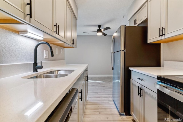 kitchen featuring ceiling fan, sink, light hardwood / wood-style floors, and stainless steel stove