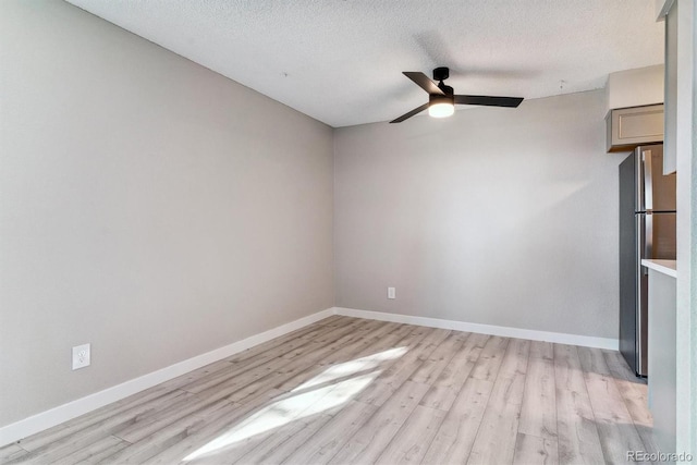 empty room with a textured ceiling, ceiling fan, and light hardwood / wood-style flooring