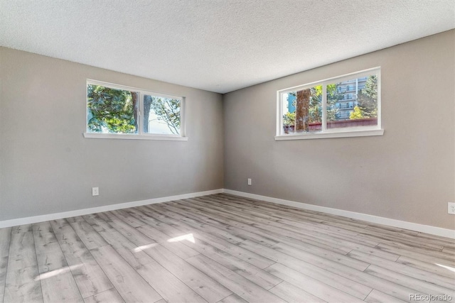 spare room with a textured ceiling and light hardwood / wood-style floors