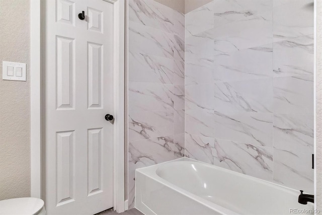 bathroom featuring tiled shower / bath and toilet