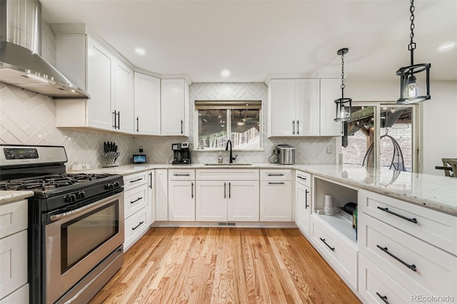 9559 Elizabeth Ct, Thornton, CO 80229 - kitchen with gas range, wall chimney range hood, light wood finished floors, backsplash, and recessed lighting