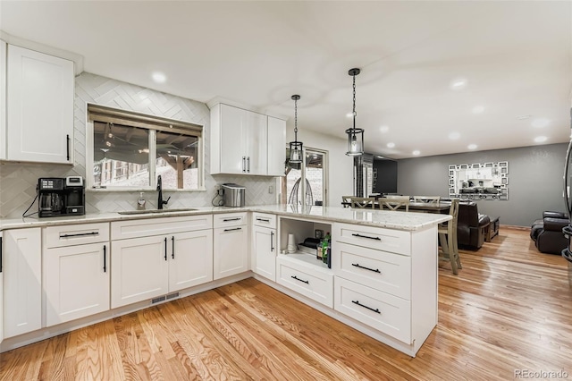 9559 Elizabeth Ct, Thornton, CO 80229 - kitchen featuring a peninsula, backsplash, light wood finished floors, white cabinetry, and recessed lighting