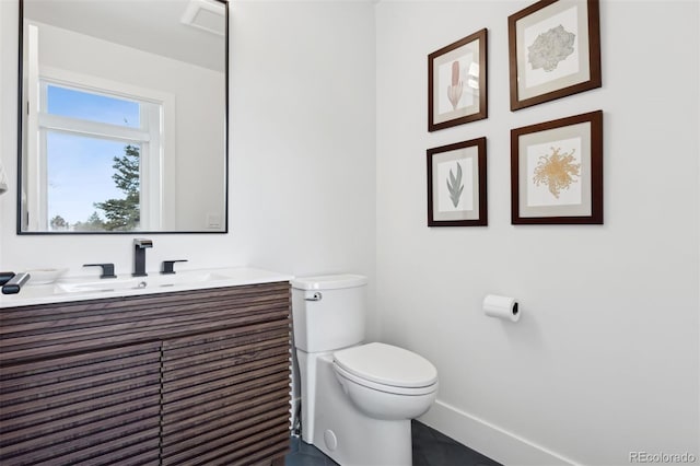 half bath featuring vanity, toilet, and baseboards