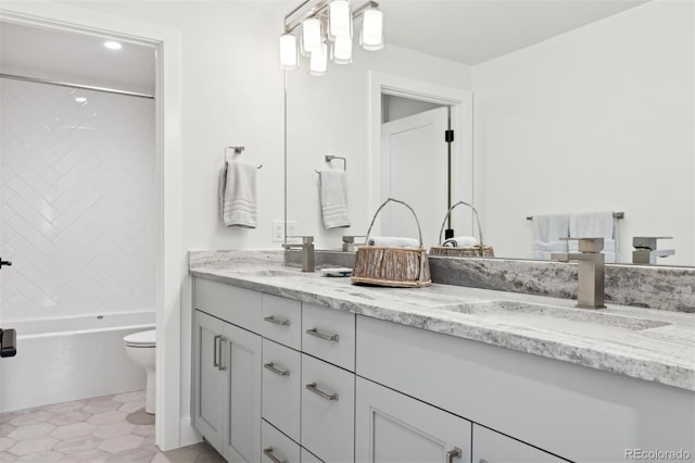 full bath featuring double vanity, toilet, a sink, and shower / bathtub combination