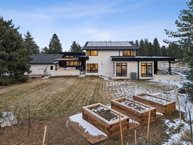 snow covered house with a vegetable garden, stucco siding, a standing seam roof, metal roof, and stone siding