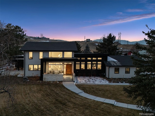 view of front of property with a mountain view, a front lawn, and stucco siding