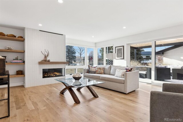 living area with light wood finished floors, a fireplace, a wealth of natural light, and recessed lighting