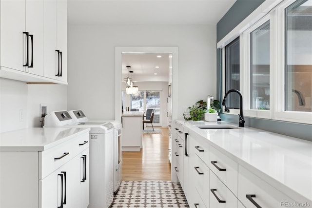 laundry area featuring light floors, recessed lighting, cabinet space, washing machine and dryer, and a sink