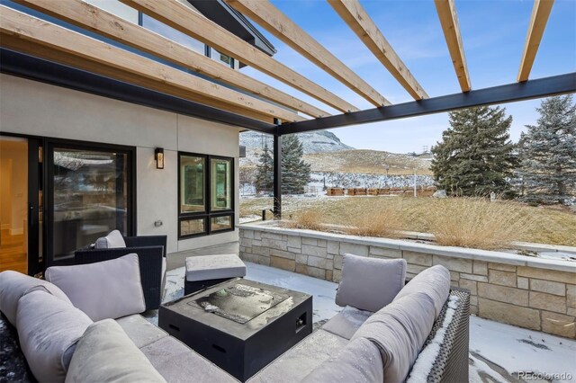 snow covered patio with an outdoor living space with a fire pit, a mountain view, and a pergola