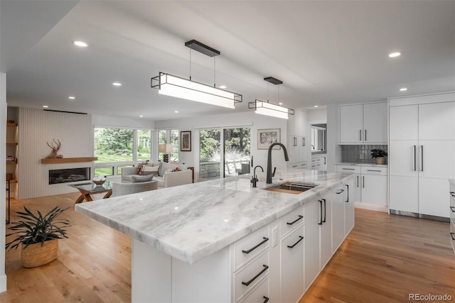 17326 W 57th Ave, Golden, CO 80403 - kitchen with a sink, light wood-style flooring, recessed lighting, a kitchen island with sink, and pendant lighting