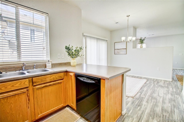 kitchen featuring sink, light hardwood / wood-style flooring, hanging light fixtures, black dishwasher, and kitchen peninsula