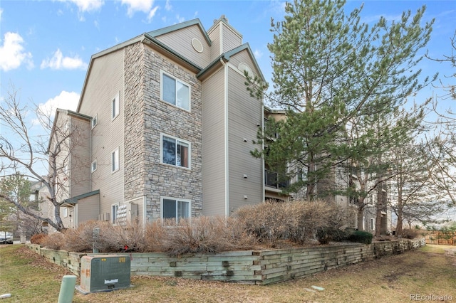 view of side of home featuring stone siding and a chimney