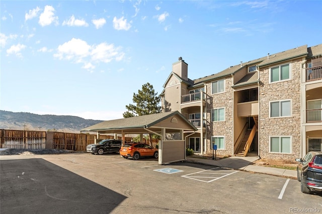 partially covered parking lot with a mountain view and fence