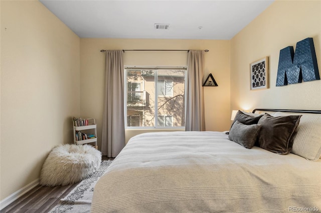 bedroom featuring visible vents, baseboards, and wood finished floors