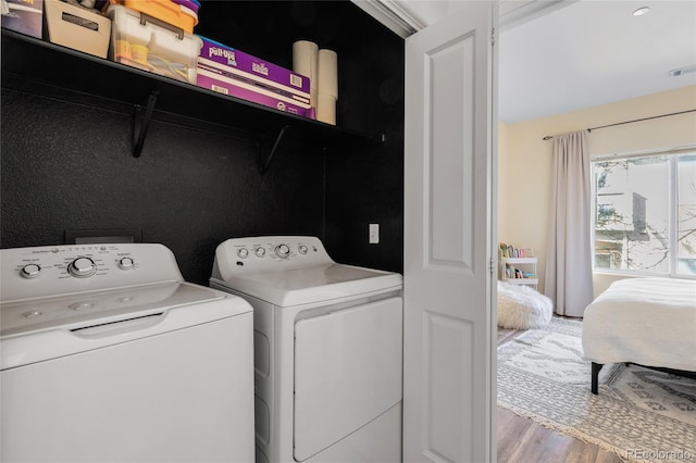 washroom featuring visible vents, wood finished floors, laundry area, and washer and clothes dryer