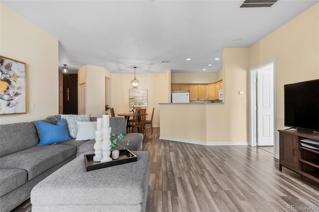 living area featuring visible vents, recessed lighting, baseboards, and wood finished floors