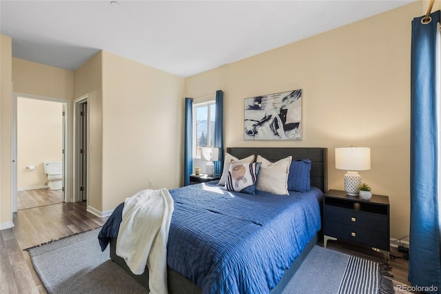 bedroom with wood finished floors, baseboards, and ensuite bathroom