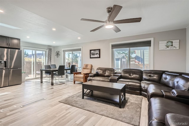 living room featuring ceiling fan, light hardwood / wood-style floors, and a textured ceiling