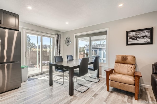 dining room with a textured ceiling, light hardwood / wood-style floors, and a wealth of natural light