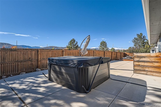 view of patio / terrace with a mountain view and a hot tub