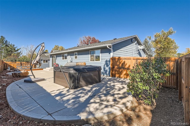 rear view of property with a hot tub and a patio area