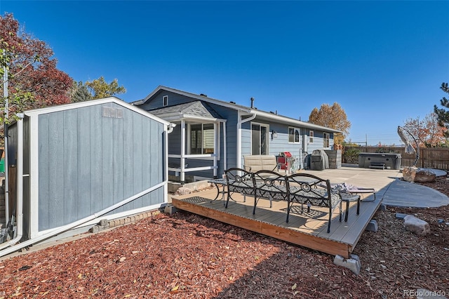 rear view of property featuring a storage unit, a deck, and a jacuzzi