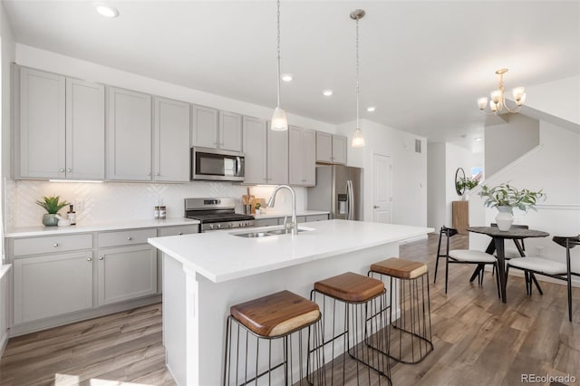 2140 Santini Trl Unit F, Littleton, CO 80129 - kitchen featuring appliances with stainless steel finishes, a sink, light wood-type flooring, a breakfast bar, and gray cabinets
