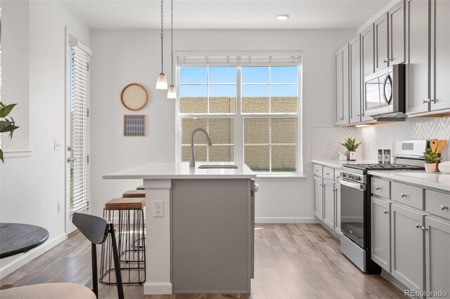 2140 Santini Trl Unit F, Littleton, CO 80129 - kitchen with appliances with stainless steel finishes, light wood finished floors, a kitchen bar, a sink, and backsplash