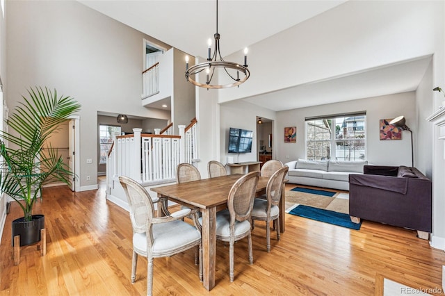 dining area featuring baseboards, light wood finished floors, stairway, and an inviting chandelier