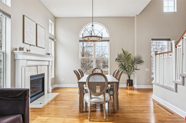 dining area featuring light wood-style flooring, a notable chandelier, visible vents, baseboards, and stairway